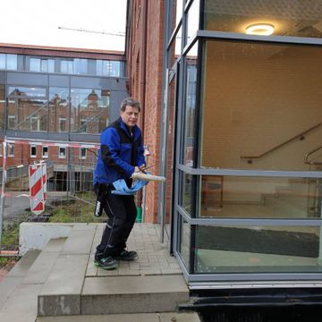 ein Mitarbeiter der Neesen Glas- und Innenreinigung reinigt eine Glasfläche im Außenbereich mit einem Abzieher und Lappen